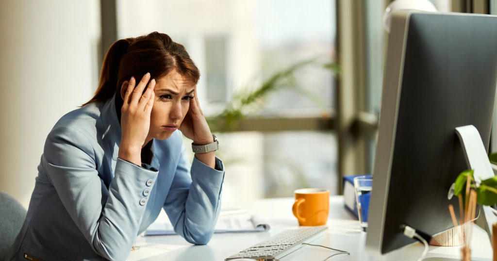 Stressed analyst holding her head at a desk, illustrating common A/B testing mistakes