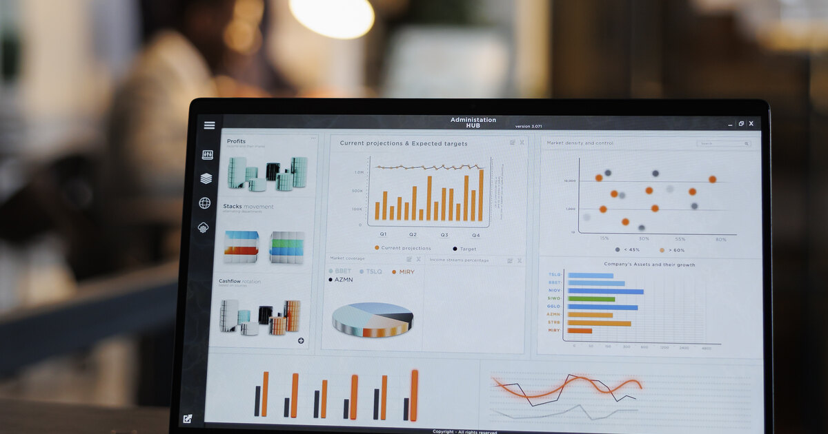 Laptop displaying a marketing analytics dashboard with projections and target charts in an office